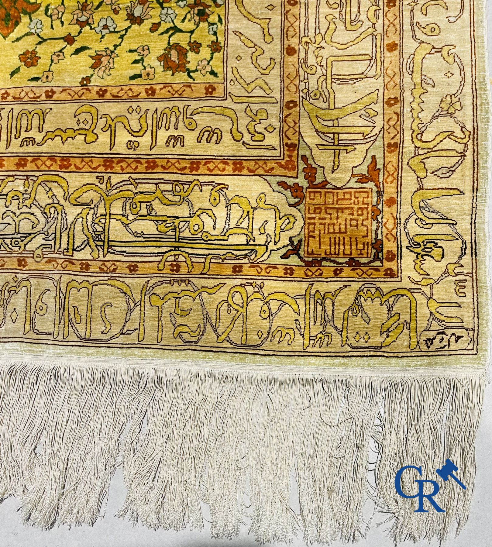 Oosterse tapijten: Een uitzonderlijk gesigneerd tapijt in zijde en gouddraad met verzen en een floraal decor.