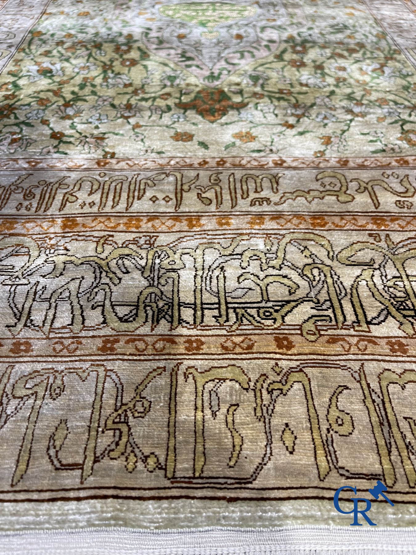Oosterse tapijten: Een uitzonderlijk gesigneerd tapijt in zijde en gouddraad met verzen en een floraal decor.