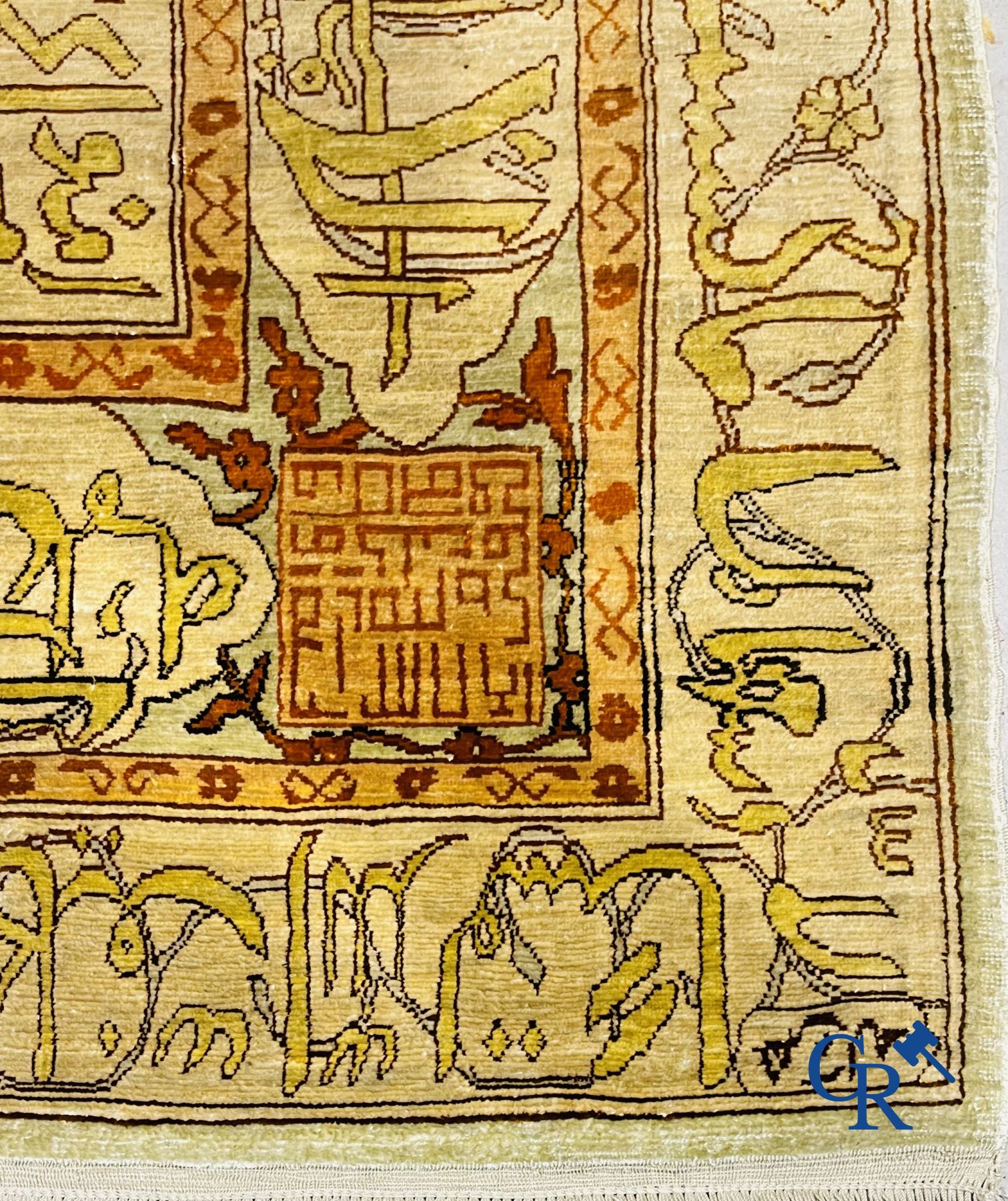 Oosterse tapijten: Een uitzonderlijk gesigneerd tapijt in zijde en gouddraad met verzen en een floraal decor.