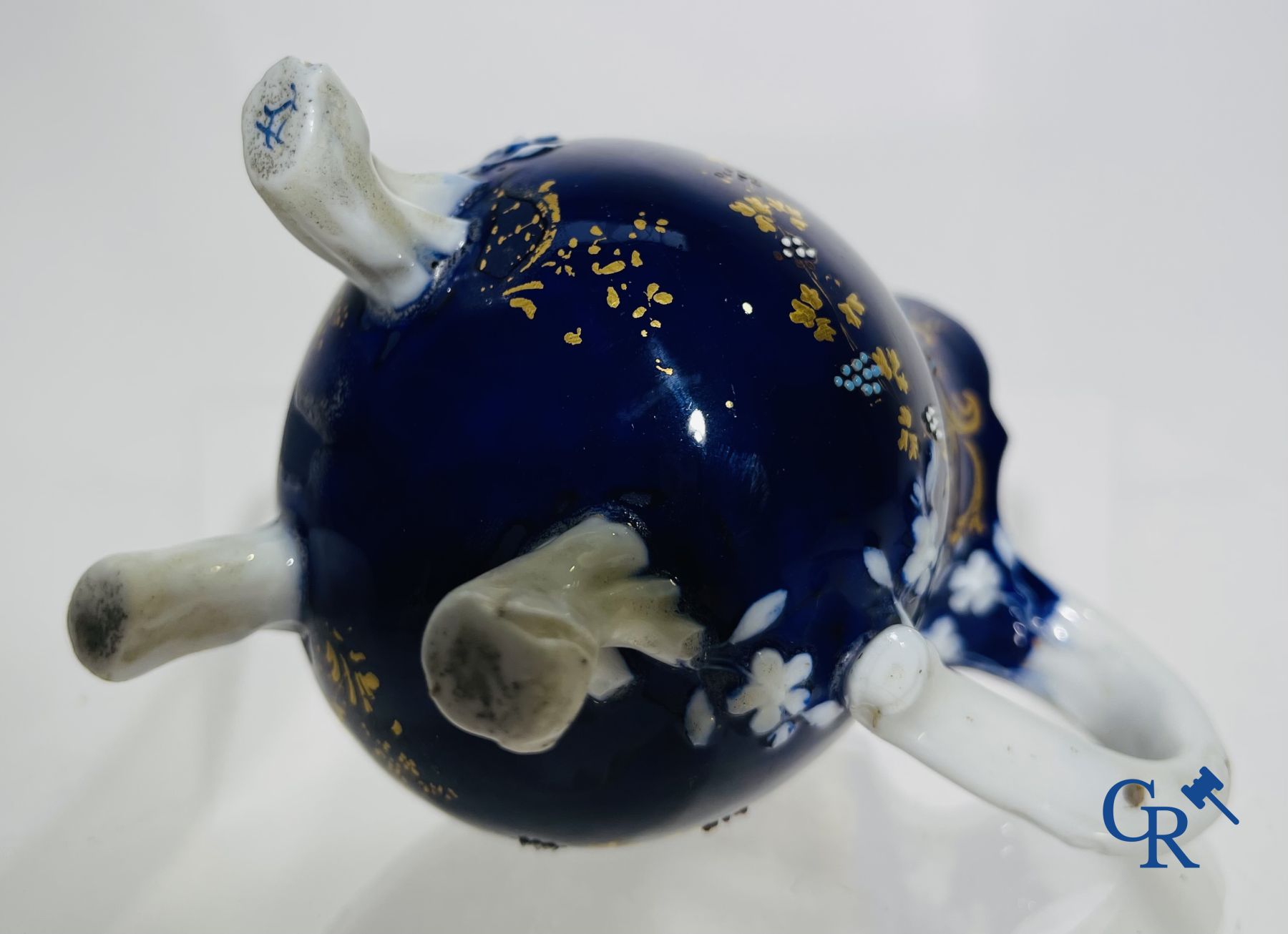 Vincennes 18de eeuw. Een driepotige melkkan in zacht porselein met lapis blauwe achtergrond.